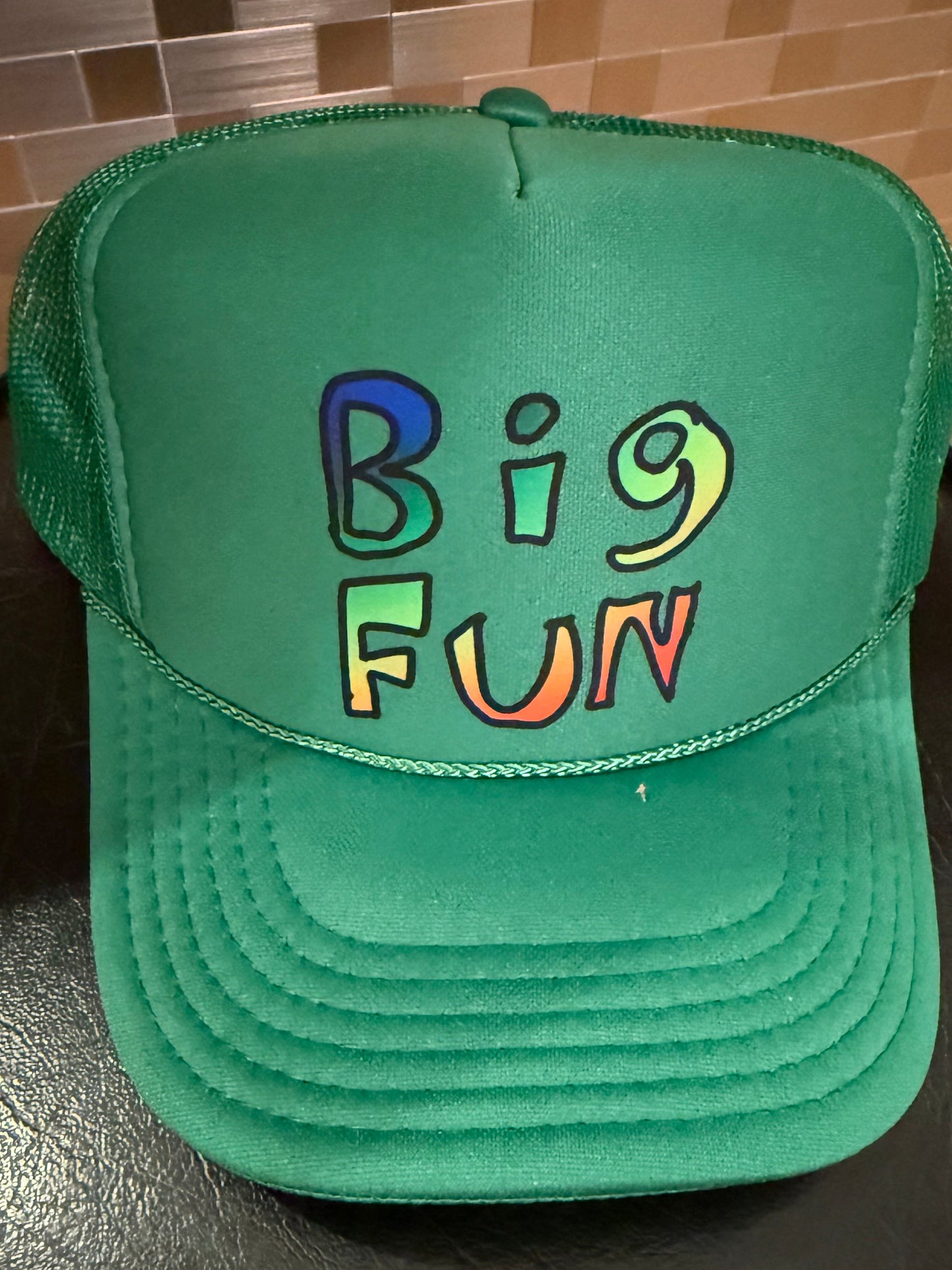 Green cap with 'Big Fun' text in colorful letters on a dark surface.